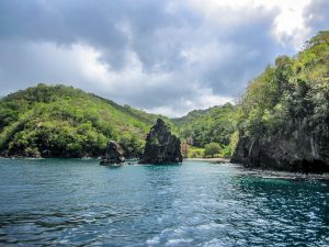 Secluded beach behind rock formations on the coast with jungle and mountains in St Vincent, The Caribbean