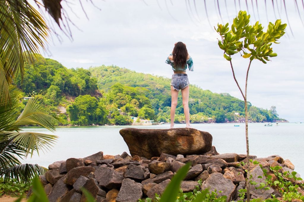 Ella on boulder by ocean on Mahe island, Seychelles