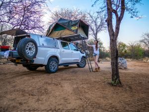 Ella with Toyota Hilux 4x4 with roof-top tent in Onguma Reserve near Etosha National Park in Namibia, Africa