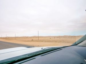 Driving through Walvis Bay in the Skeleton Coast with sand dunes in background, Namibia Africa