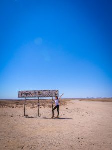 Ella at Tropic of Capricorn Sign in Namib Desert, Namibia, Africa