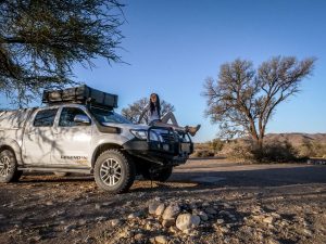 Ella on Toyota Hilux 4x4 with rooftop tent in Namib Desert campsite, Namibia, Africa
