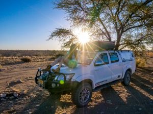 Ella on Toyota Hilux 4x4 with rooftop tent in Namib Desert campsite, Namibia, Africa