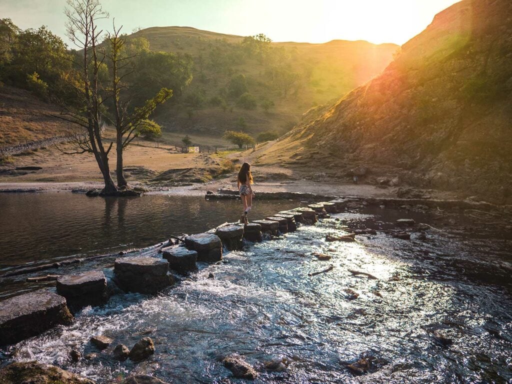 Woman crossing Dovedale Stepping Stones in the Peak District