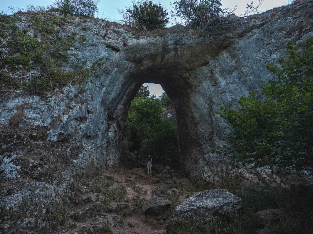 Ella standing under Reynard&rsquo;s Arch in Dovedale Valley Peak district