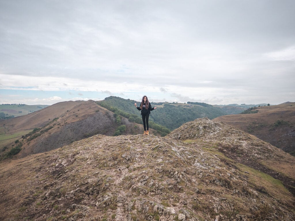 Ella McKendrick on Thorpe Cloud summit with the stepping stones in the valley behind
