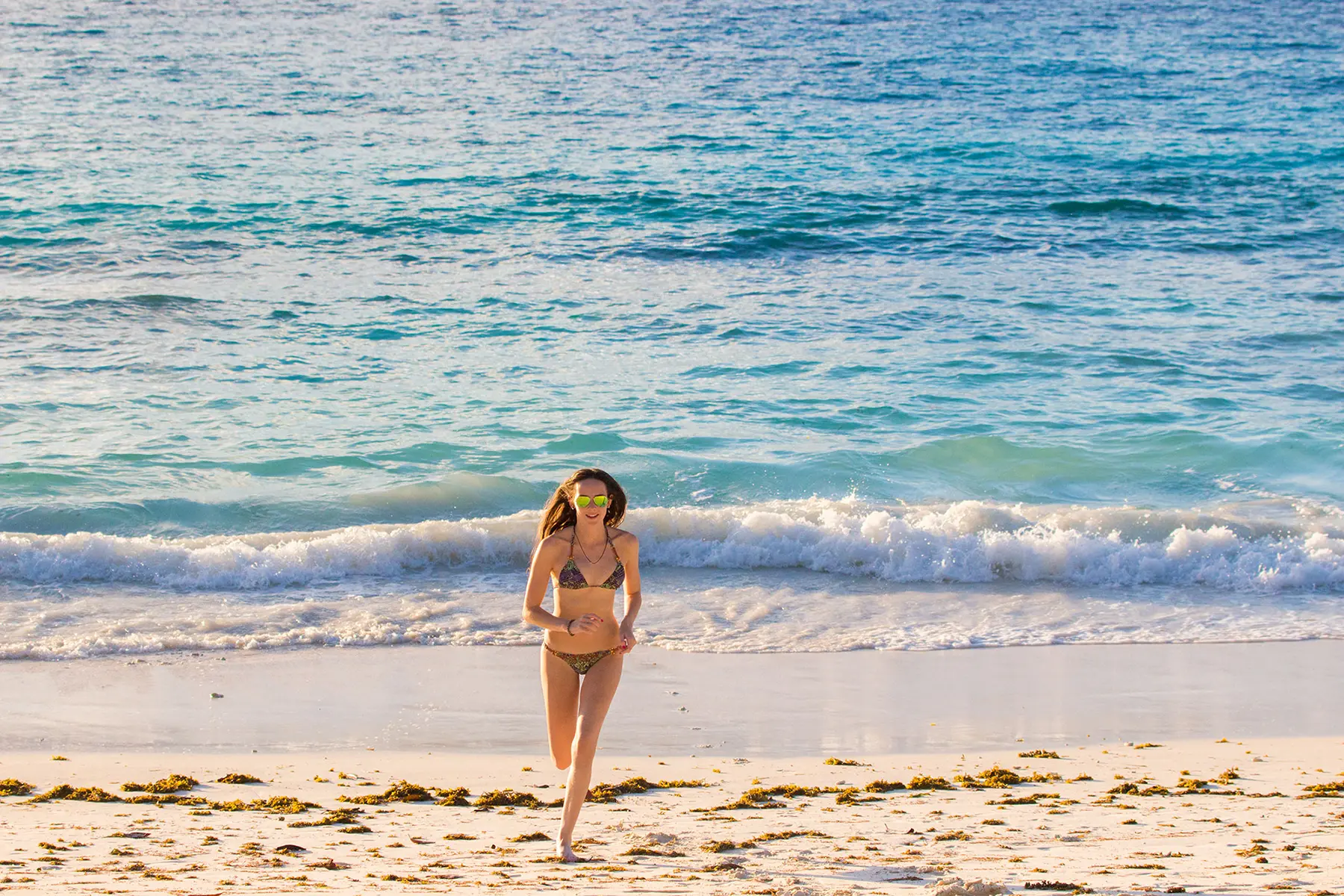 Ella McKendrick running on sandy beach, Zanzibar