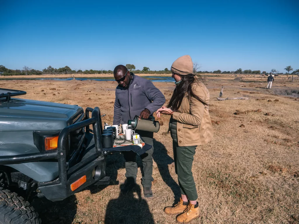 Ella McKendrick drinking tea by safari truck in Khwai, Botswana