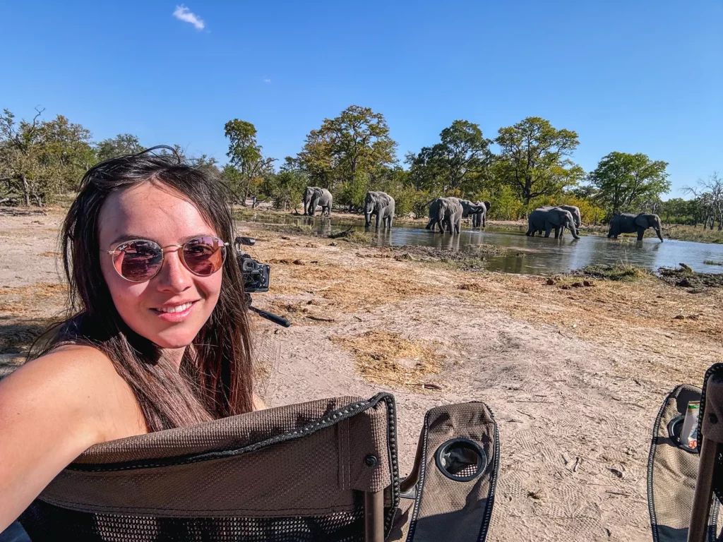 Ella McKendrick sitting in front of an family of elephants in a waterhole in Moremi Game Reserve, Botswana.