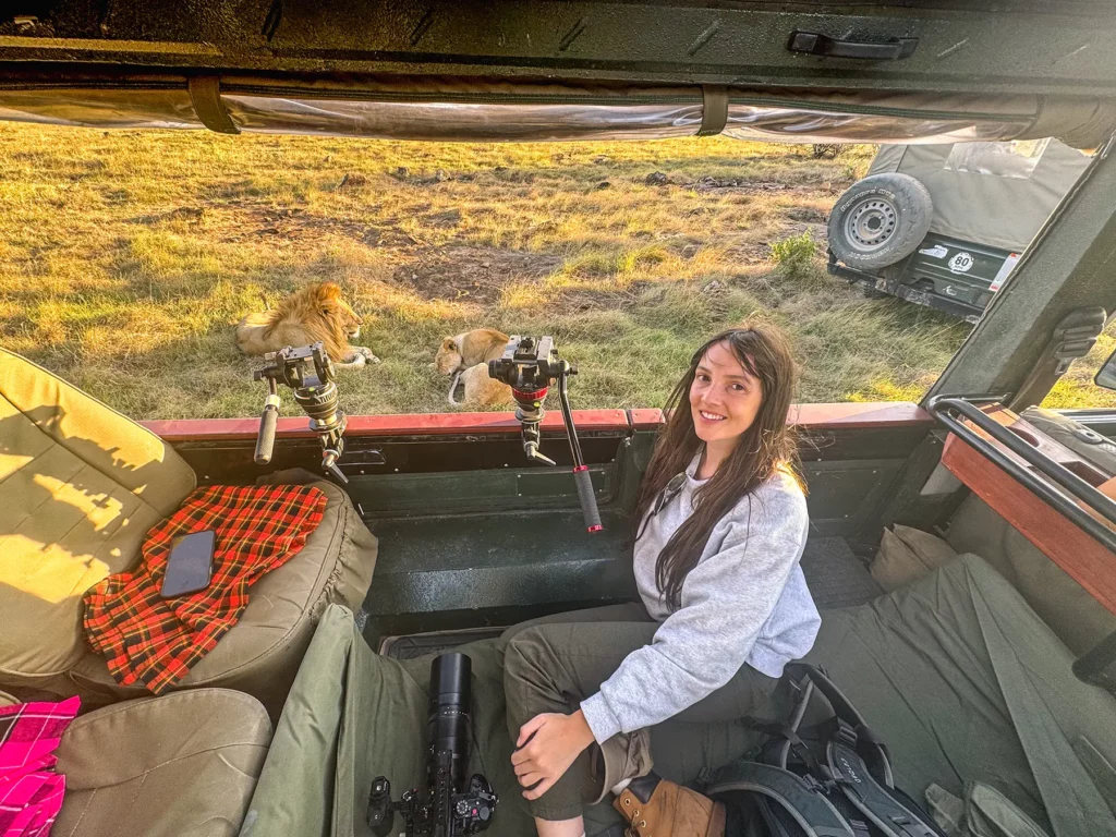 Ella McKendrick next to lions in the Maasai Mara, Kenya