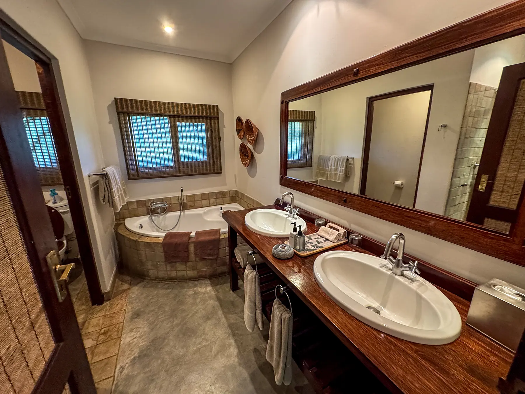 En-suite bathroom with twin basins on a wooden vanity and a corner bathtub on safari in Sabi Sand Game Reserve, South Africa