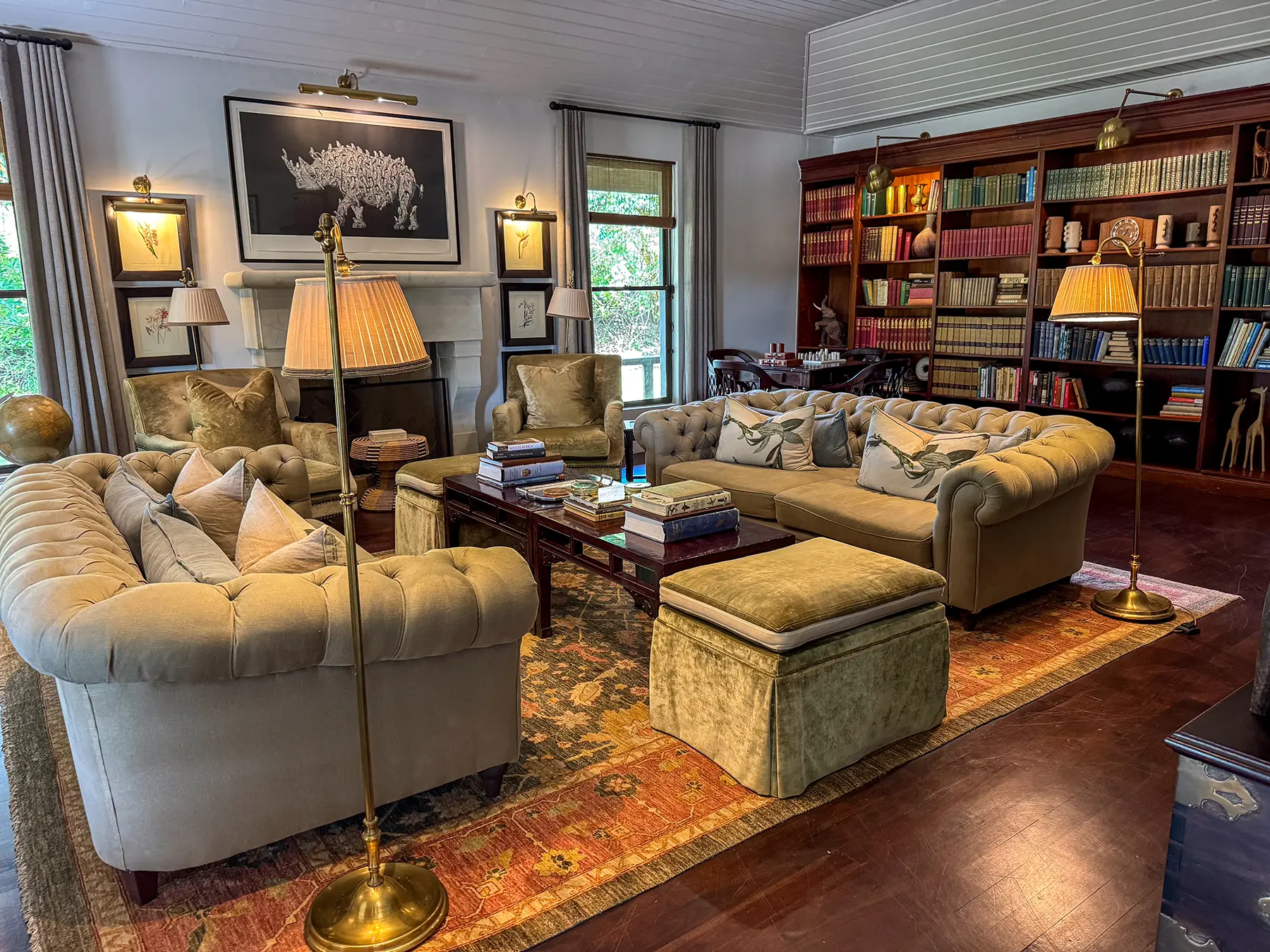 A library lounge with tufted Chesterfield sofas and floor-to-ceiling bookshelves at a safari lodge on safari in the Sabi Sand Game Reserve, South Africa