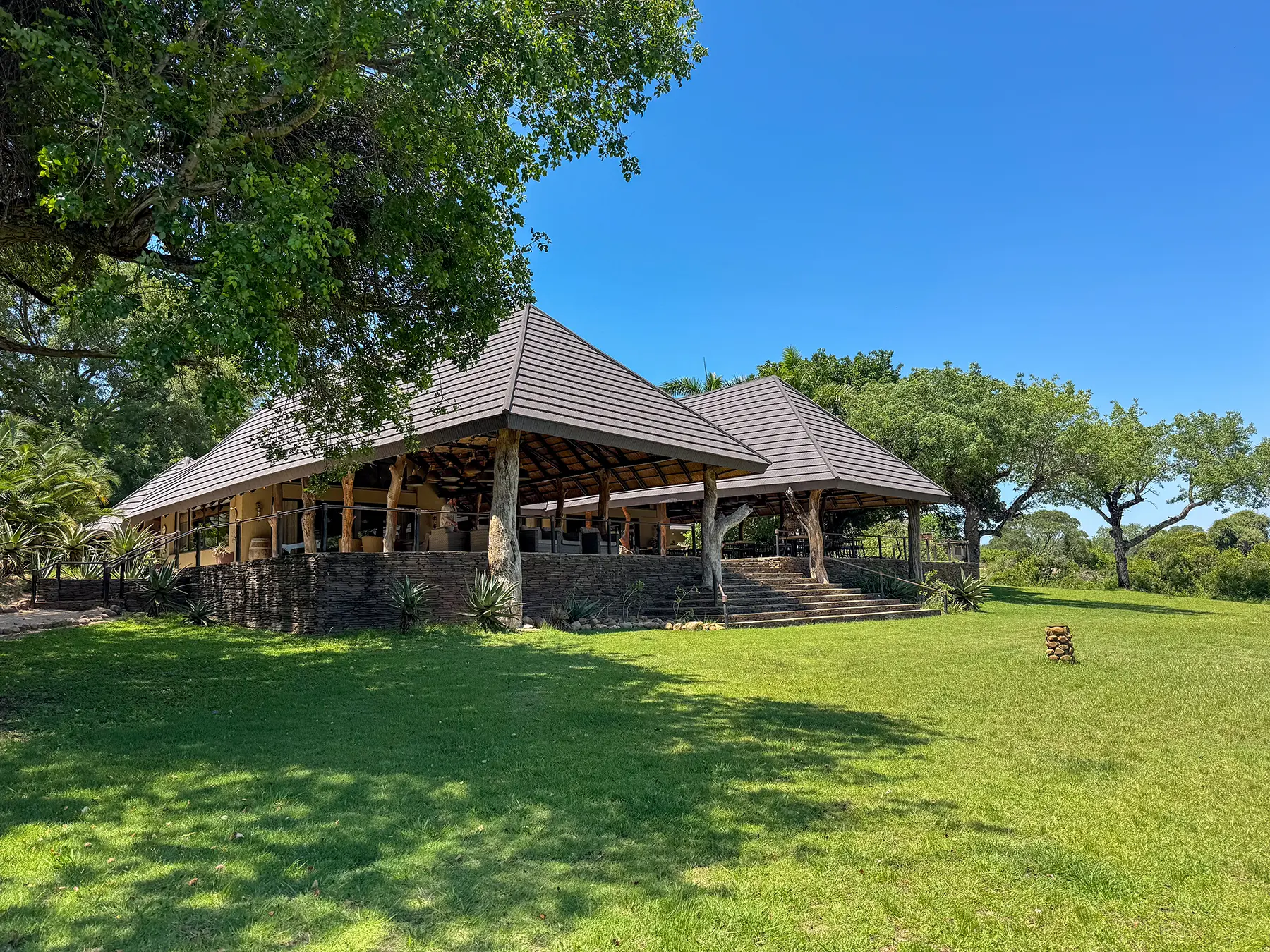 Main lodge building with thatched roof and green lawns under a blue sky on safari in Sabi Sand Game Reserve, South Africa