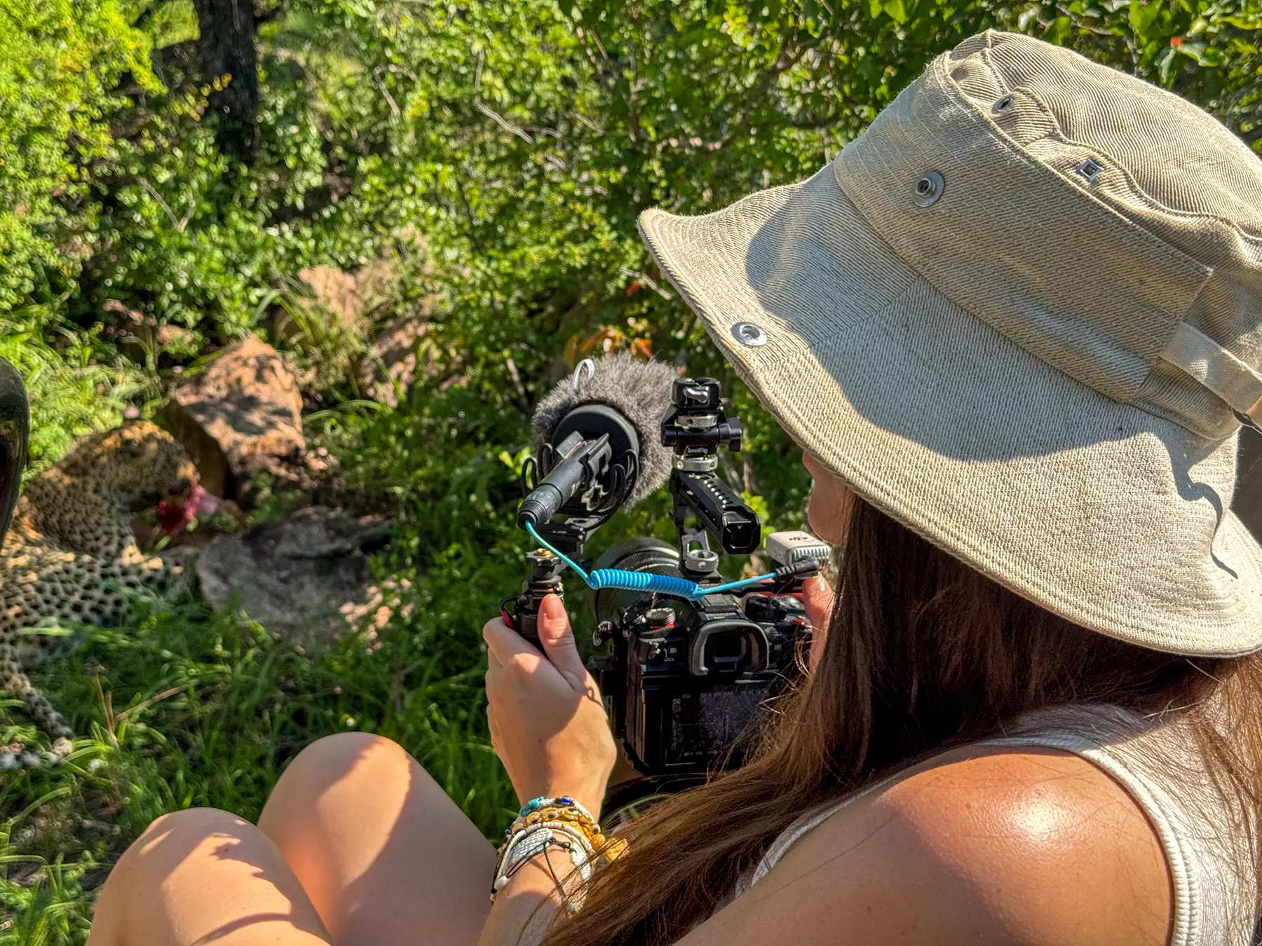 Ella McKendrick filming a leopard with a camera and external microphone on safari in the Sabi Sand Game Reserve, South Africa