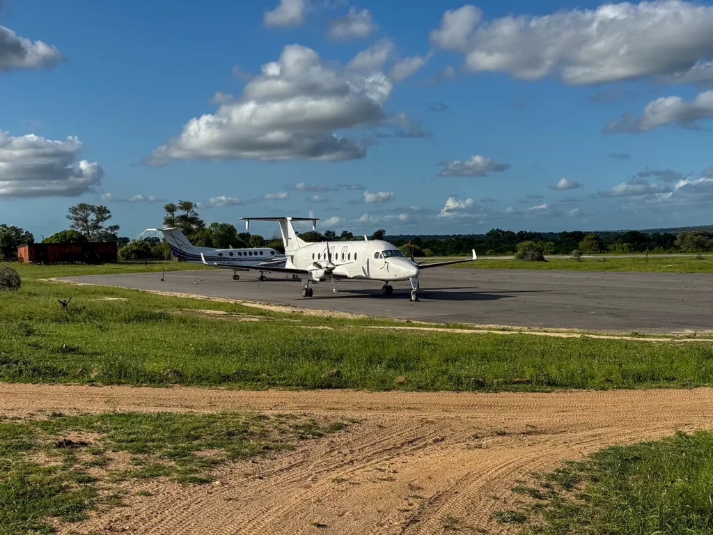 Small charter planes parked on a bush airstrip surrounded by green vegetation on a flight in South Africa