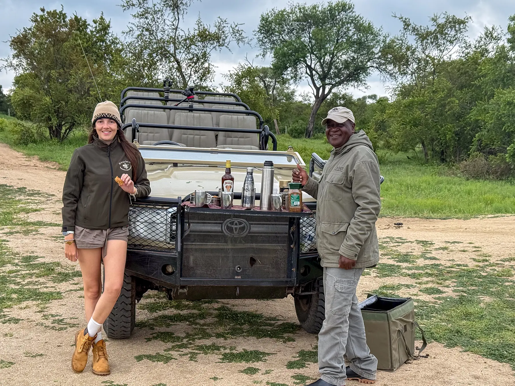 Ella McKendrick with a local South African safari guide enjoying a bush drinks stop beside a Toyota game drive vehicle on safari in South Africa