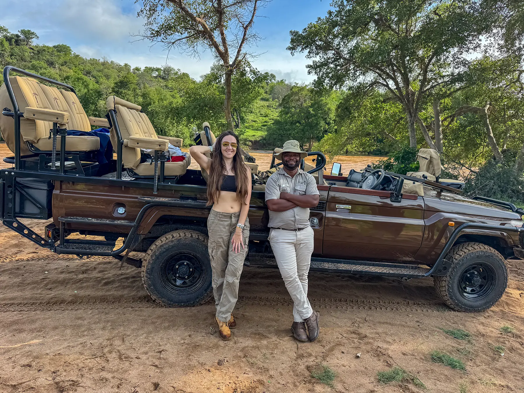Ella McKendrick with a local South African safari guide standing in front of an open-top safari vehicle on safari in South Africa