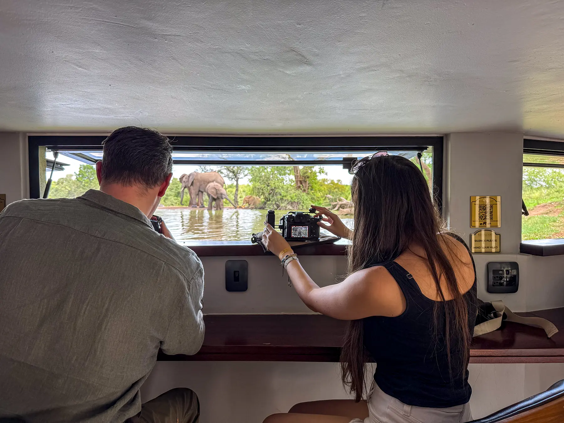 Ella McKendrick and a fellow guest filming elephants at a waterhole from a photography hide on safari in the Timbavati Private Nature Reserve, South Africa