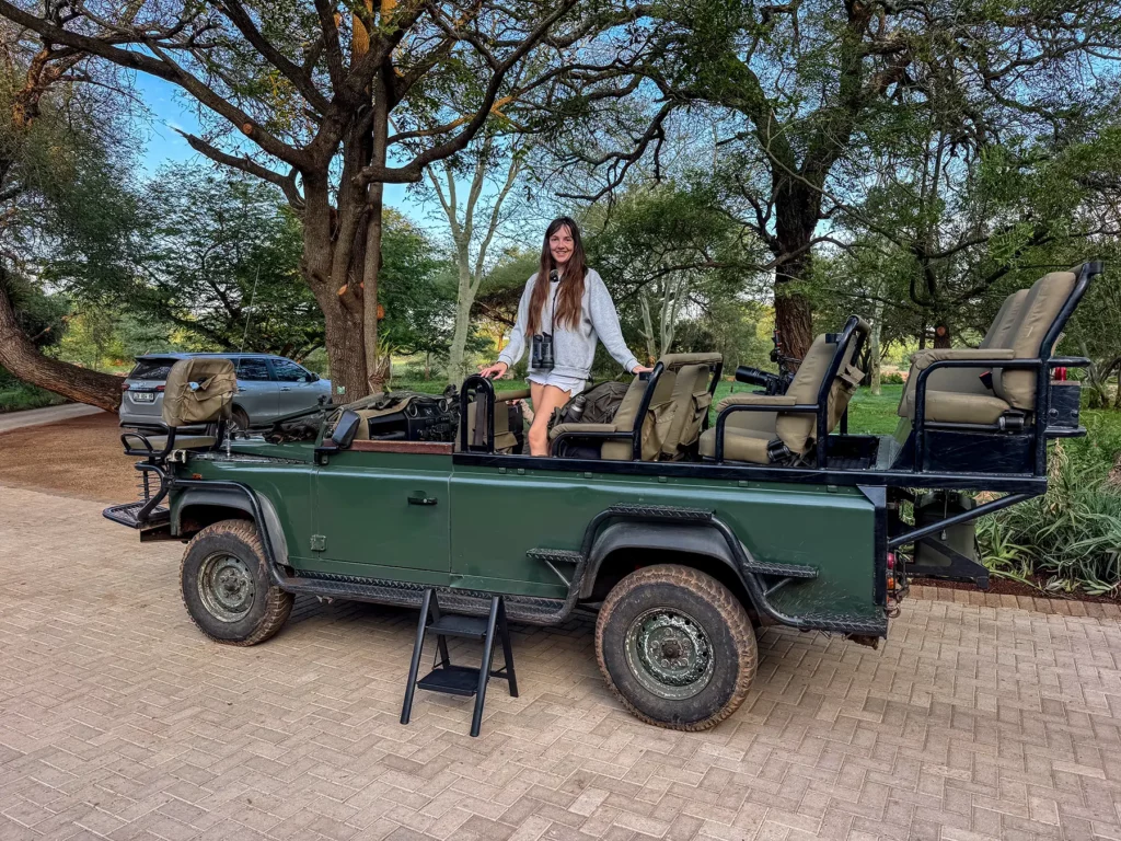 Ella McKendrick standing in an open safari vehicle parked at a lodge on safari in the Timbavati Private Nature Reserve, South Africa