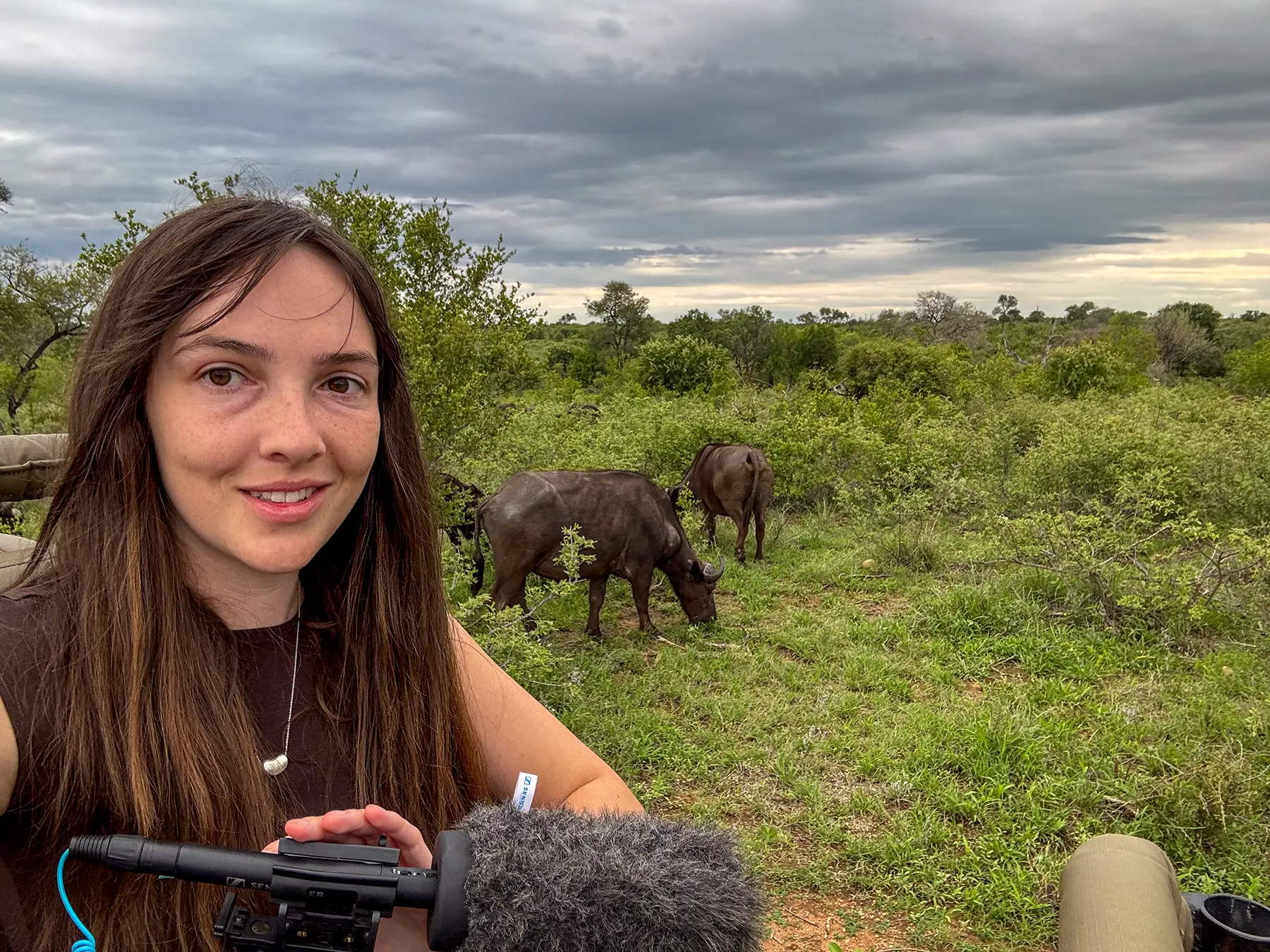 Ella McKendrick taking a selfie with buffalo grazing behind her on safari in the Timbavati Private Nature Reserve, South Africa