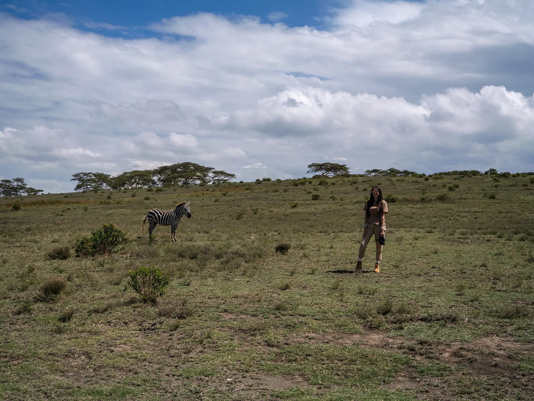Ella McKendrick standing on open grassland with a zebra nearby at Lake Naivasha in Kenya