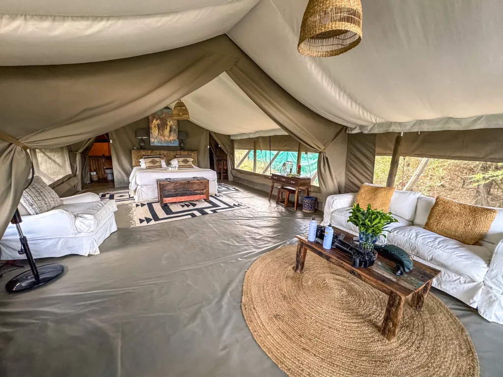 Spacious tented bedroom with lounge area and African textiles at Maasai Mara National Reserve, Kenya