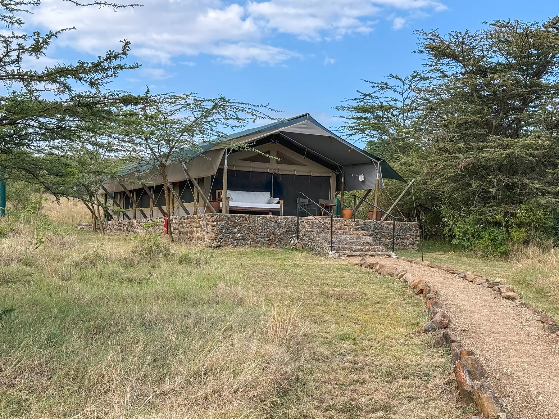 Safari tent exterior with stone terrace and swing seat at Maasai Mara National Reserve in Kenya