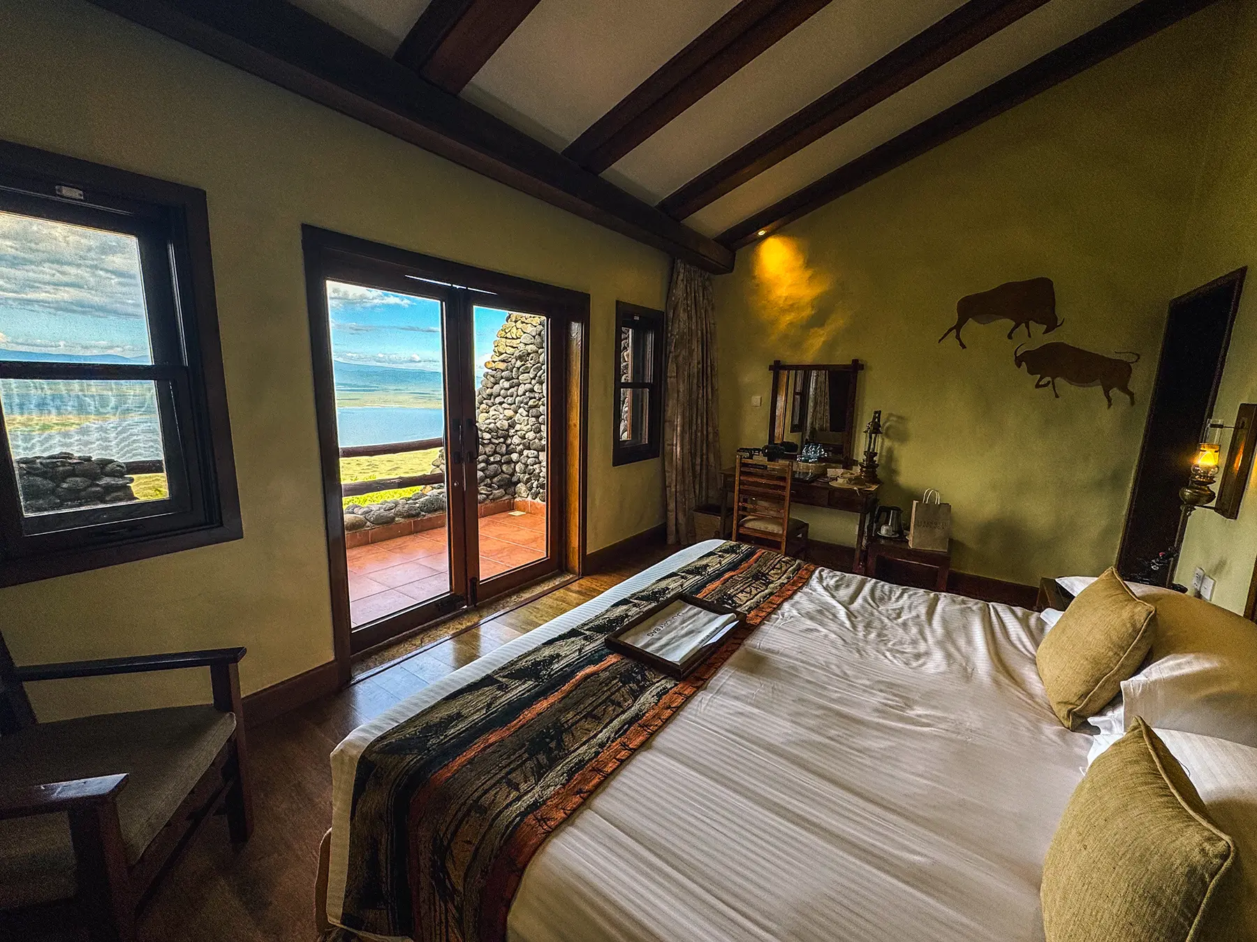 Lodge bedroom with crater view through open terrace doors in the Ngorongoro Conservation Area, Tanzania
