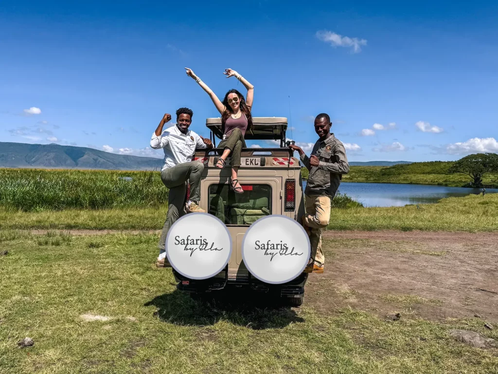 Ella McKendrick sitting on top of a safari vehicle with two guides posing at the back in Ngorongoro Crater, Tanzania