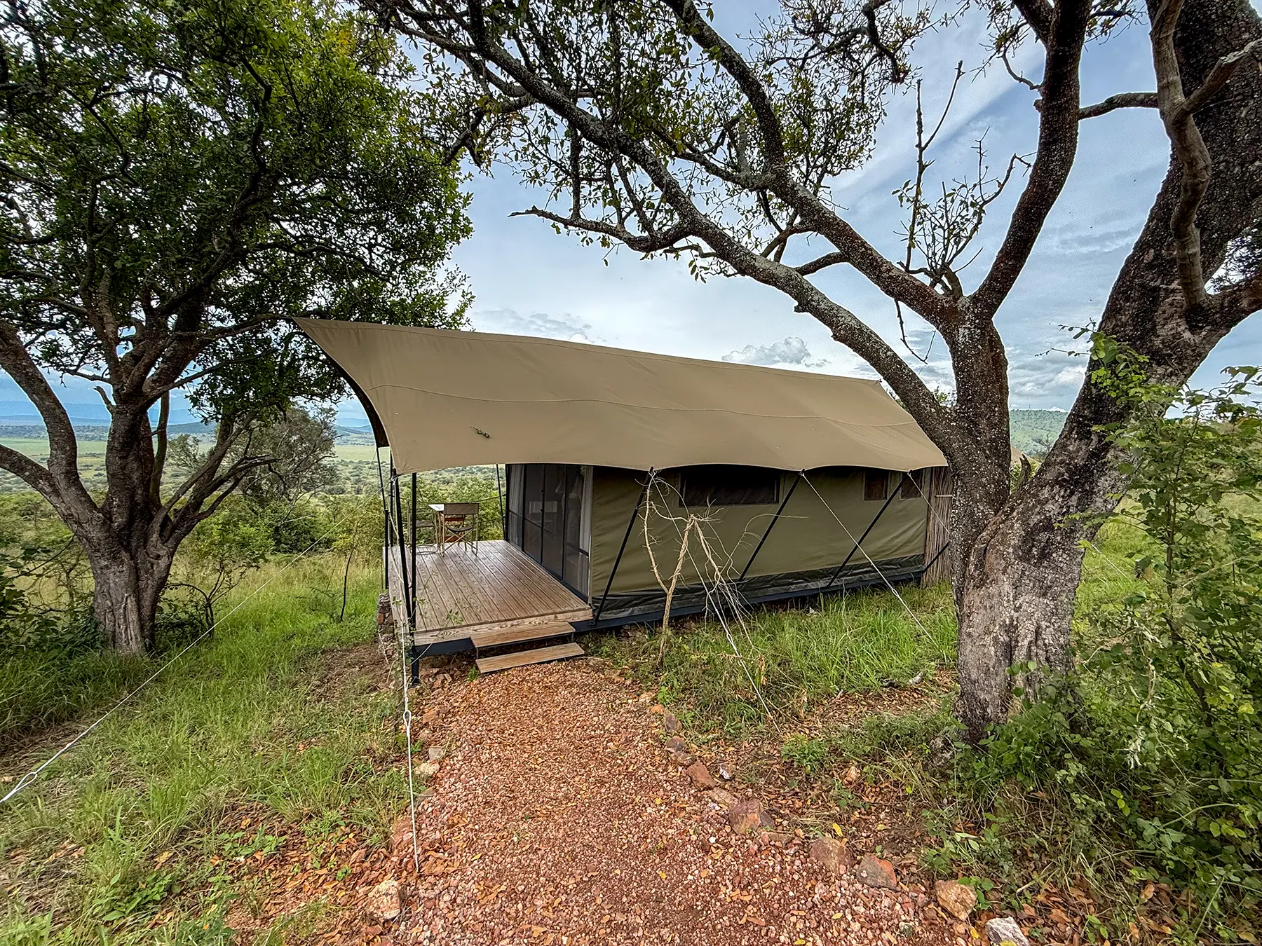 Canvas guest tent with private deck framed by acacia trees on a hillside at Karenge Bush Camp in Akagera National Park, Rwanda