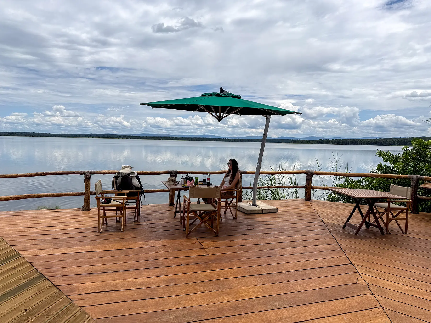Lakeside deck with green parasol and dining table overlooking Lake Ihema at Ruzizi Tented Camp in Akagera National Park, Rwanda