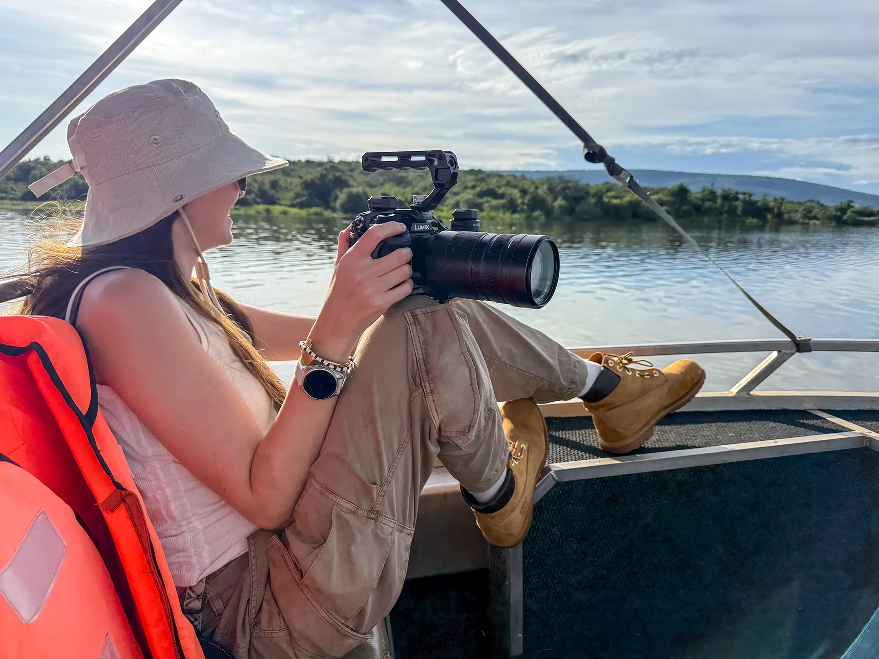 Ella McKendrick holding long lens camera while seated on safari boat at Lake Ihema, Rwanda