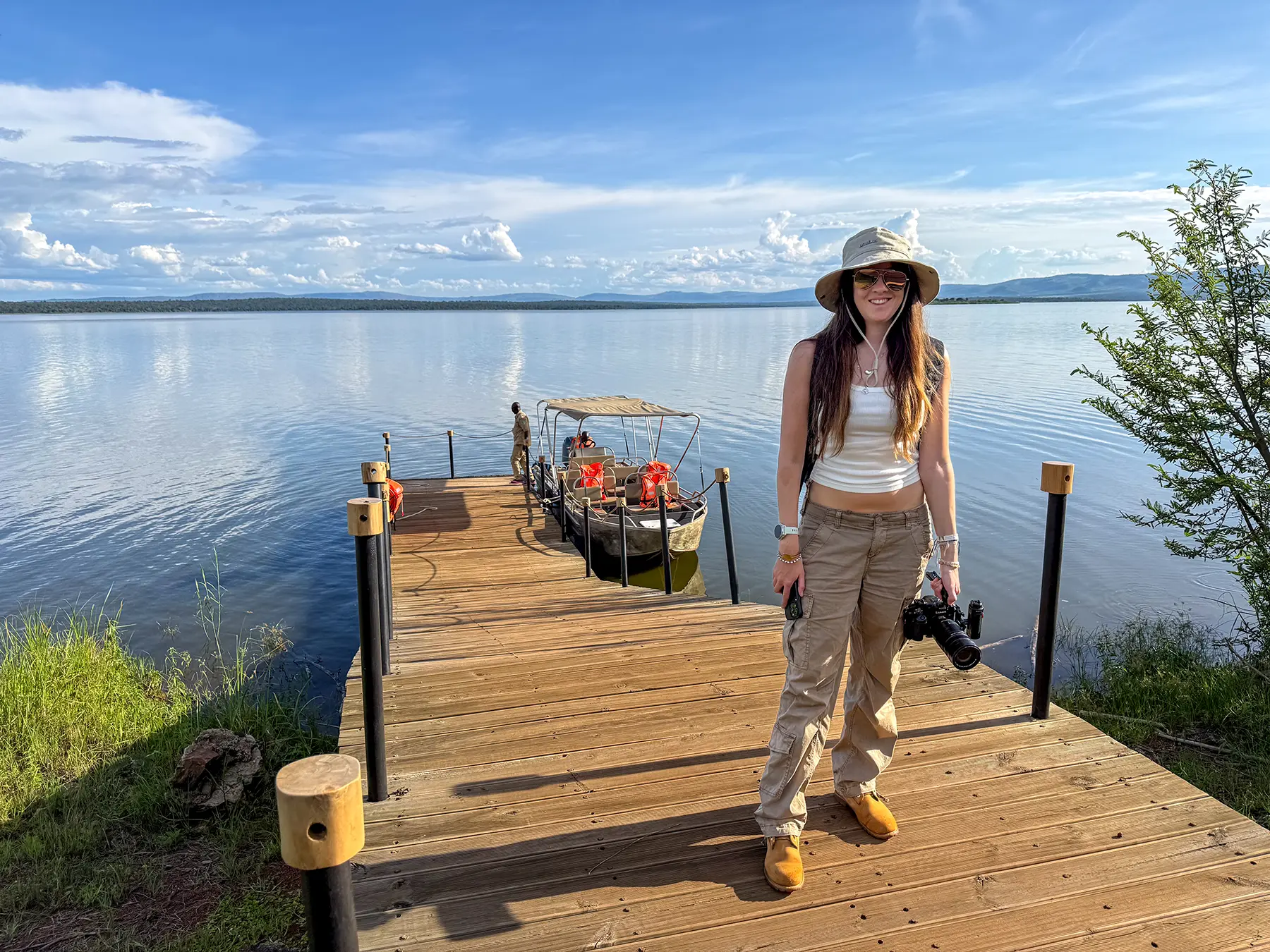 Ella McKendrick standing on wooden jetty beside small boat at Lake Ihema in Akagera, Rwanda