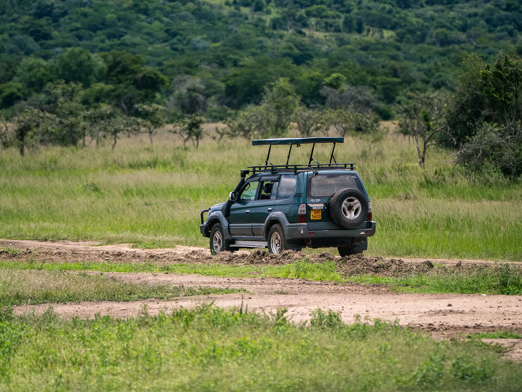 A small safari vehicle parked on a green grass clearing on safari in Akagera National Park, Rwanda