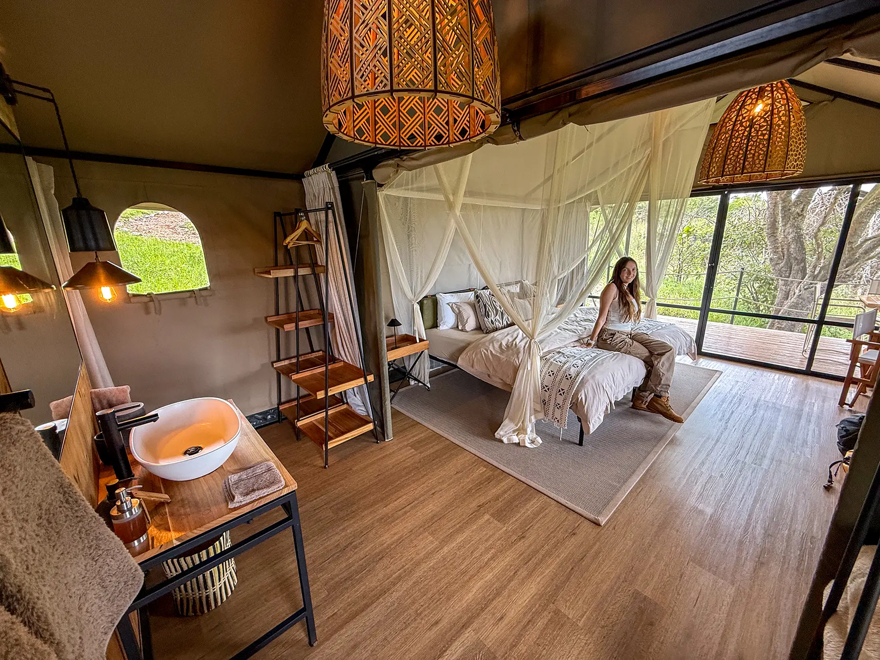 Ella McKendrick on draped four-poster bed inside tented suite with stair detail at Karenge Bush Camp in Akagera National Park, Rwanda
