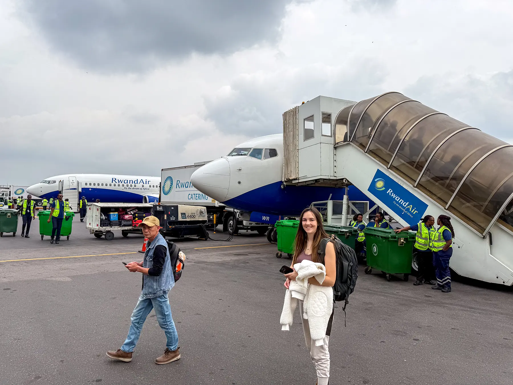 Ella McKendrick walking on tarmac beside RwandAir aircraft and ground crew at Kigali International Airport, Rwanda