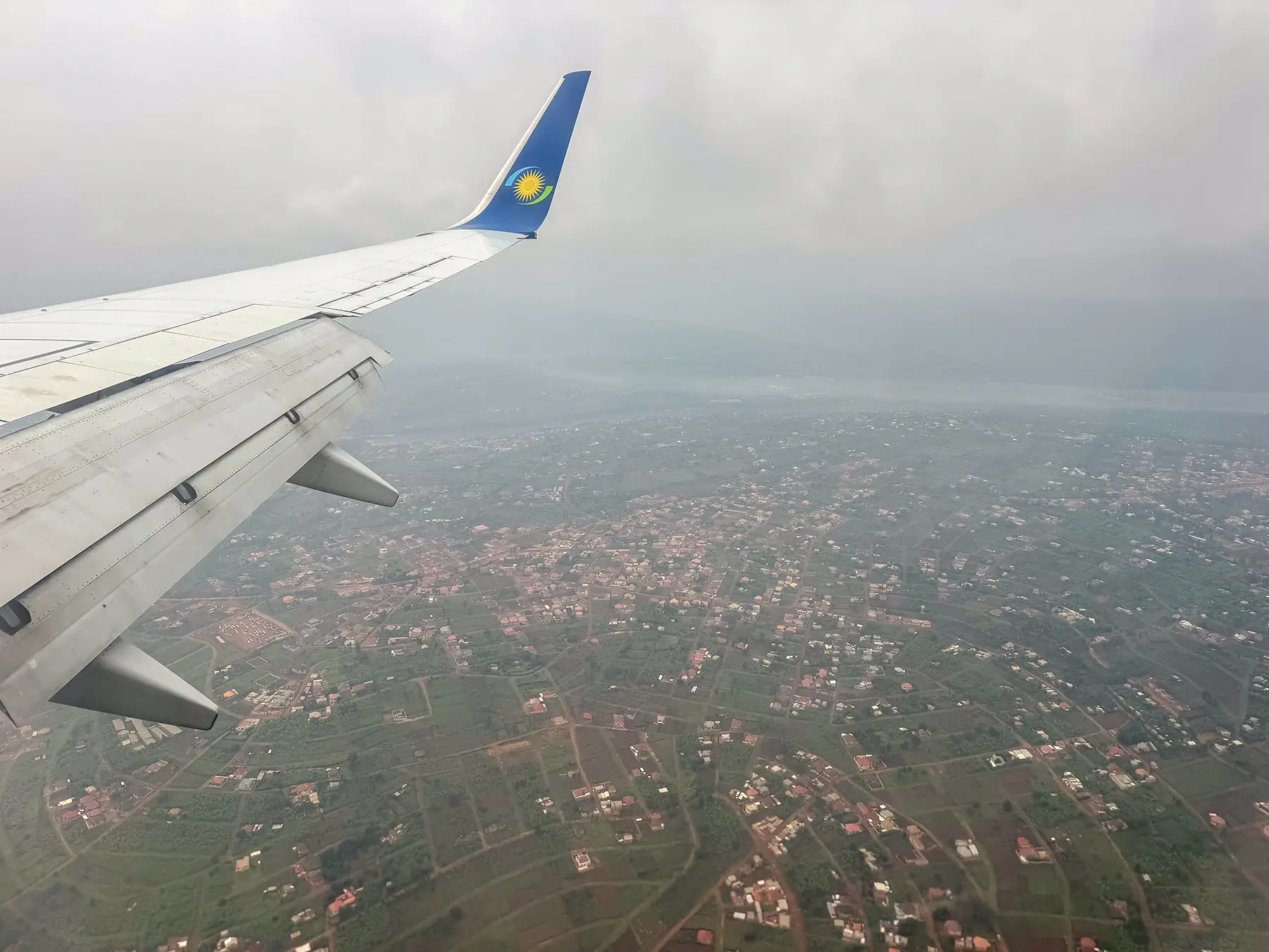 RwandAir wingtip with Rwandan flag livery above Kigali cityscape at Kigali International Airport, Rwanda
