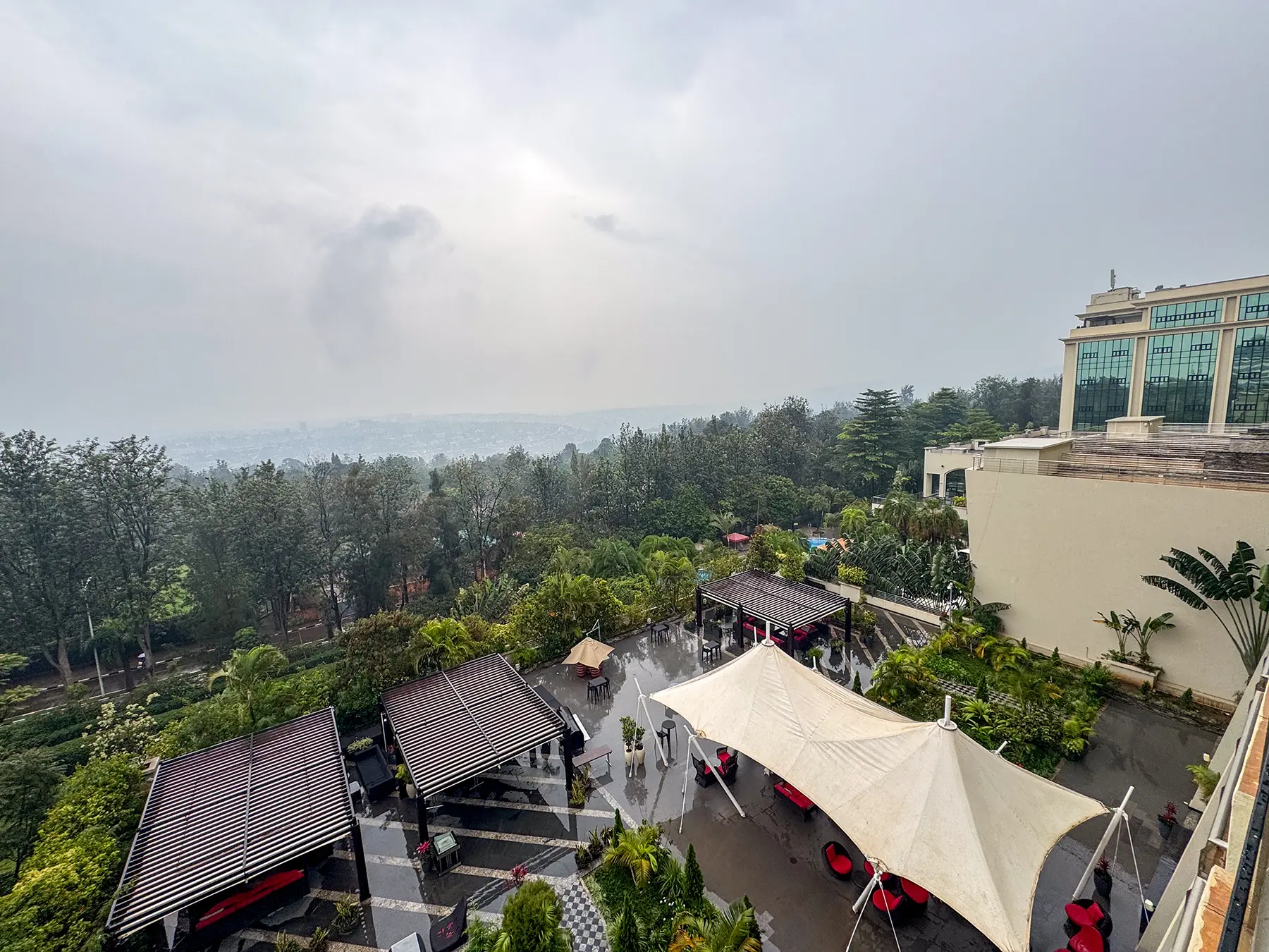 View over hotel gardens pool cabanas and Kigali hills under hazy sky at Kigali Marriott in Kigali, Rwanda