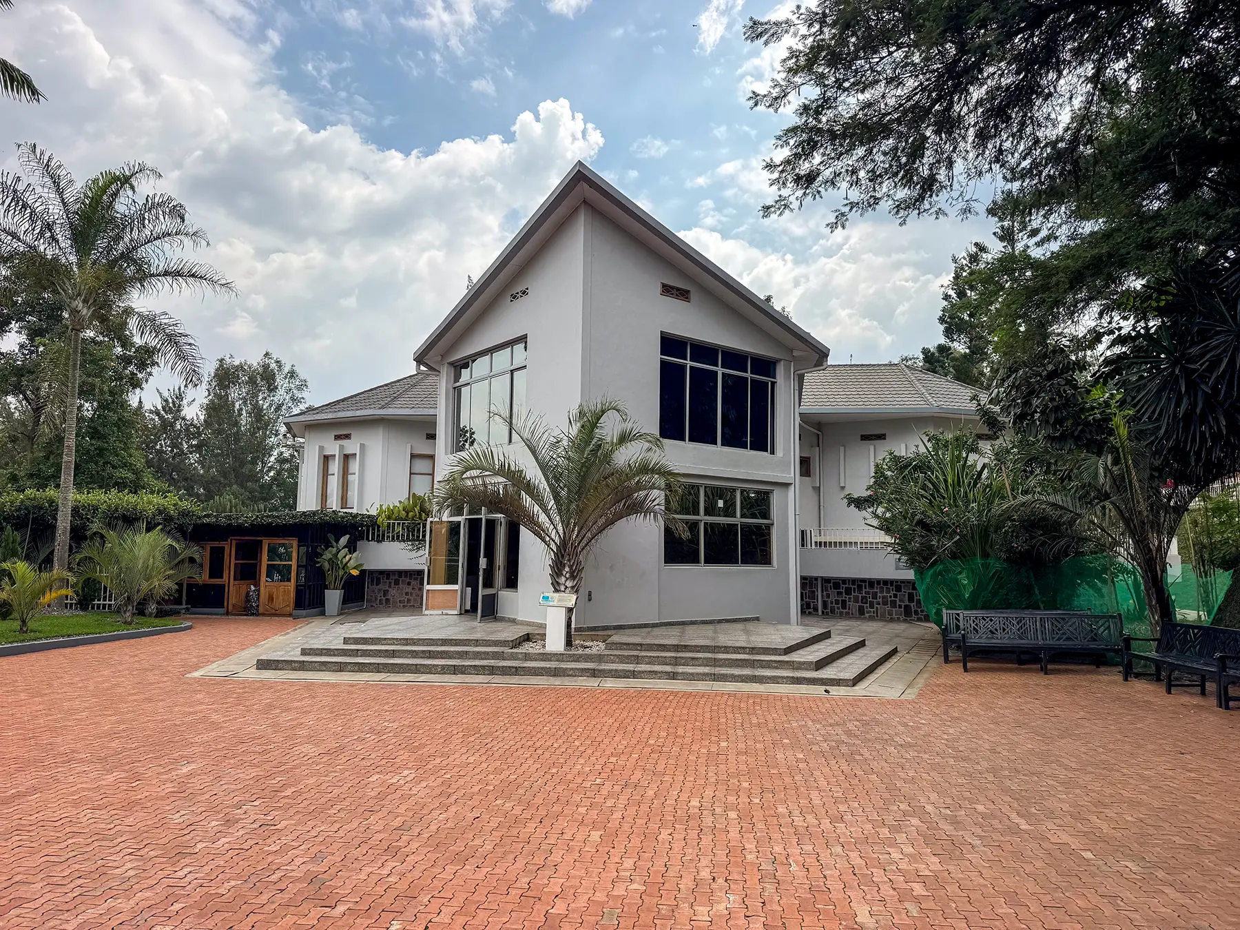 White memorial building with pitched roof and tall windows above a paved forecourt at Kigali Genocide Memorial in Kigali, Rwanda