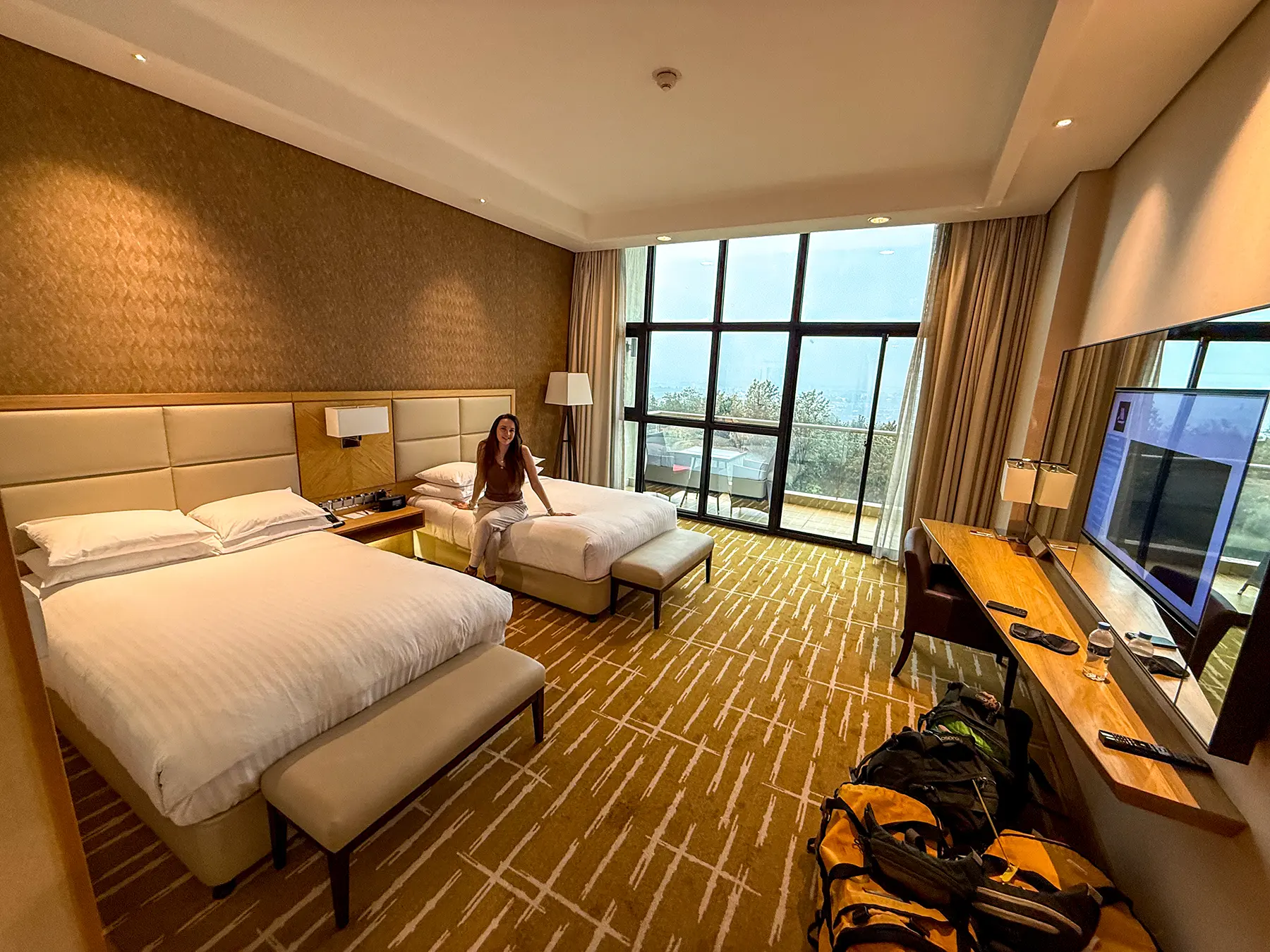 Ella McKendrick on bed in twin hotel room with city view at Kigali Marriott in Kigali, Rwanda