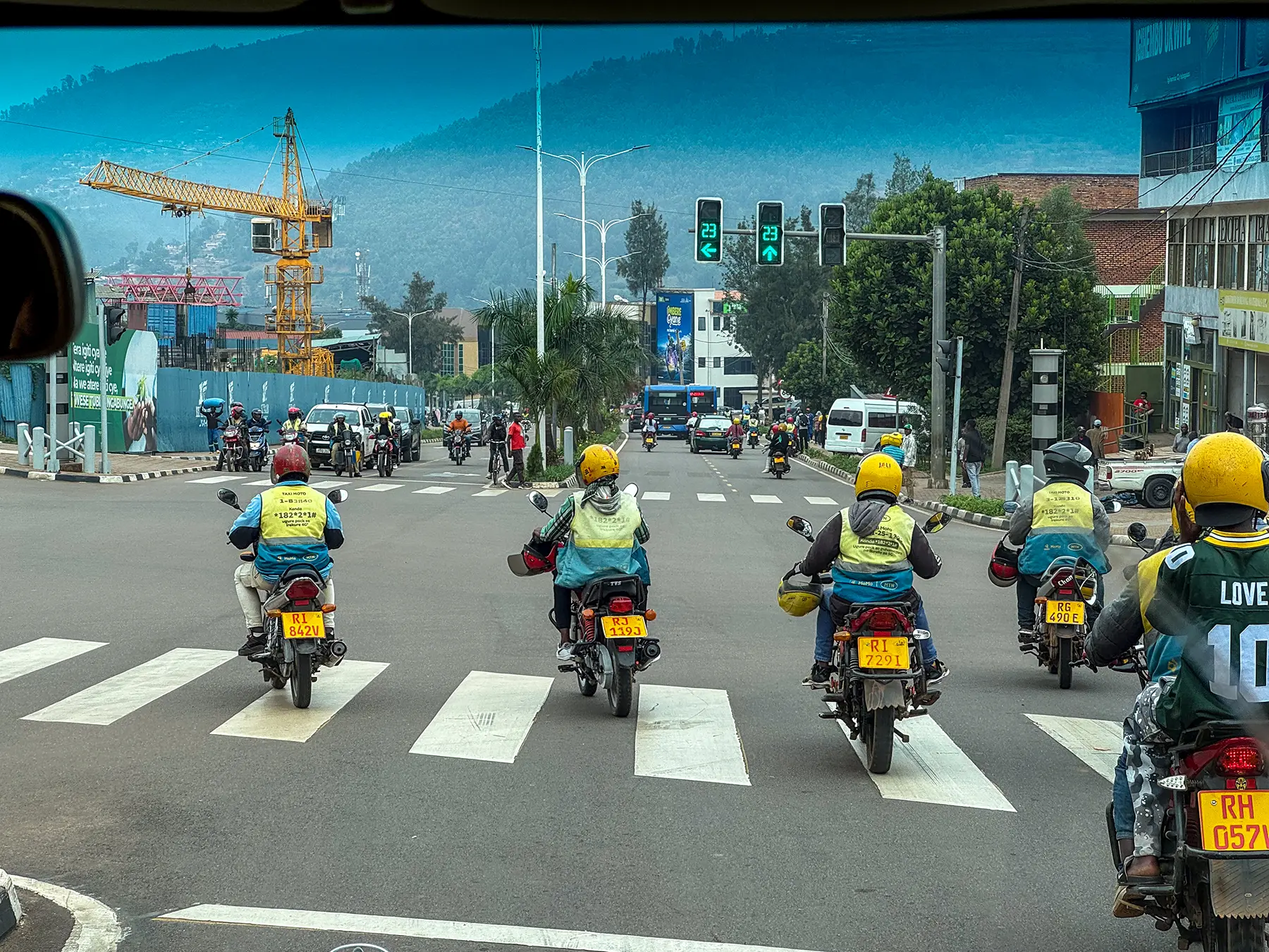 Moto taxis lined up at a traffic junction with hills behind at city junction in Kigali, Rwanda