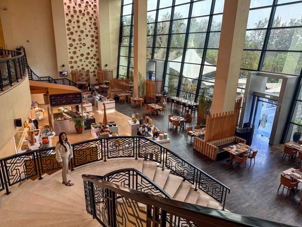 Ella McKendrick on curved staircase in double height lobby and dining area at Kigali Marriott in Kigali, Rwanda
