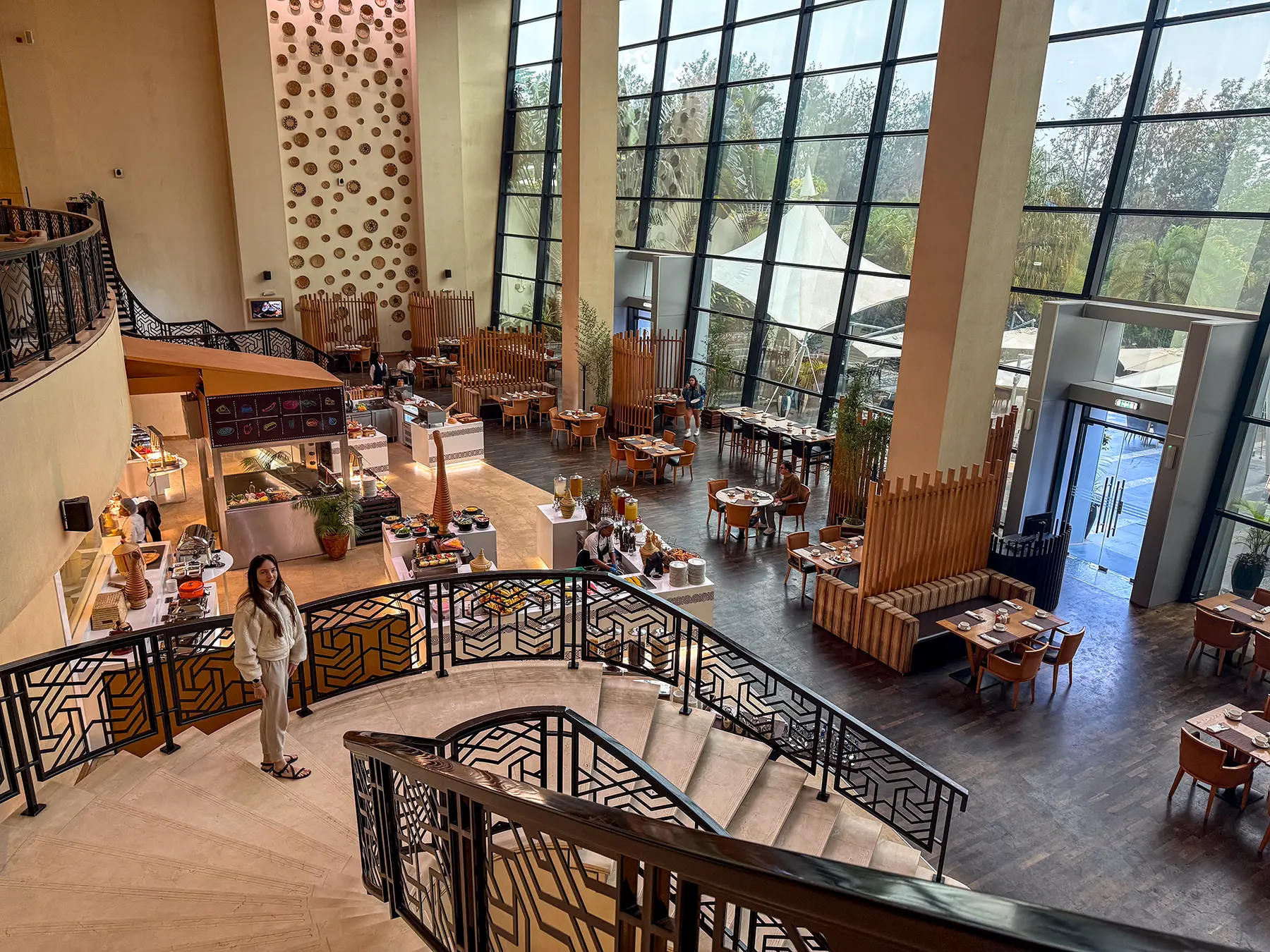 Ella McKendrick on curved staircase in double height lobby and dining area at Kigali Marriott in Kigali, Rwanda
