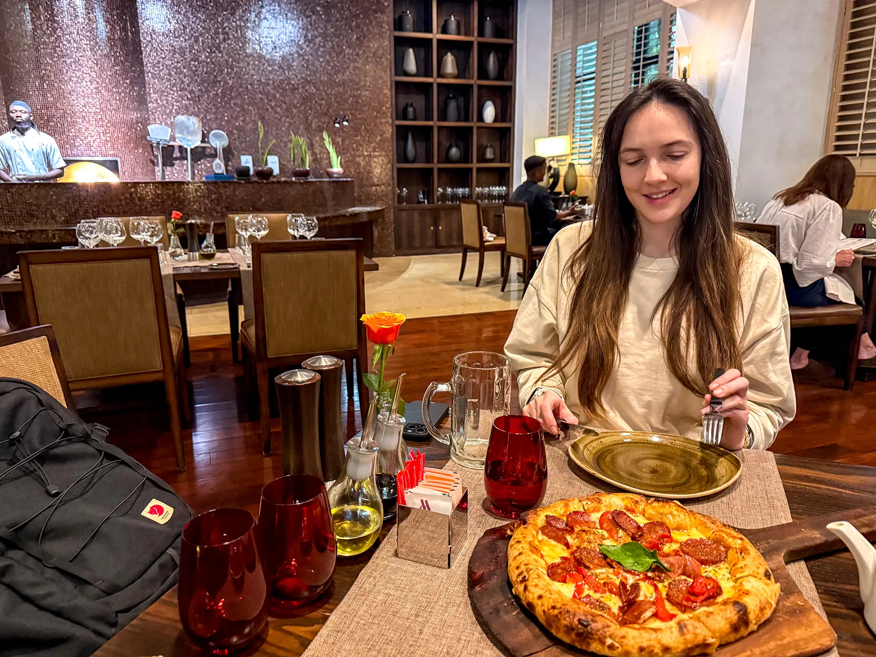 Ella McKendrick seated with pepperoni pizza in hotel restaurant at Kigali Marriott in Kigali, Rwanda