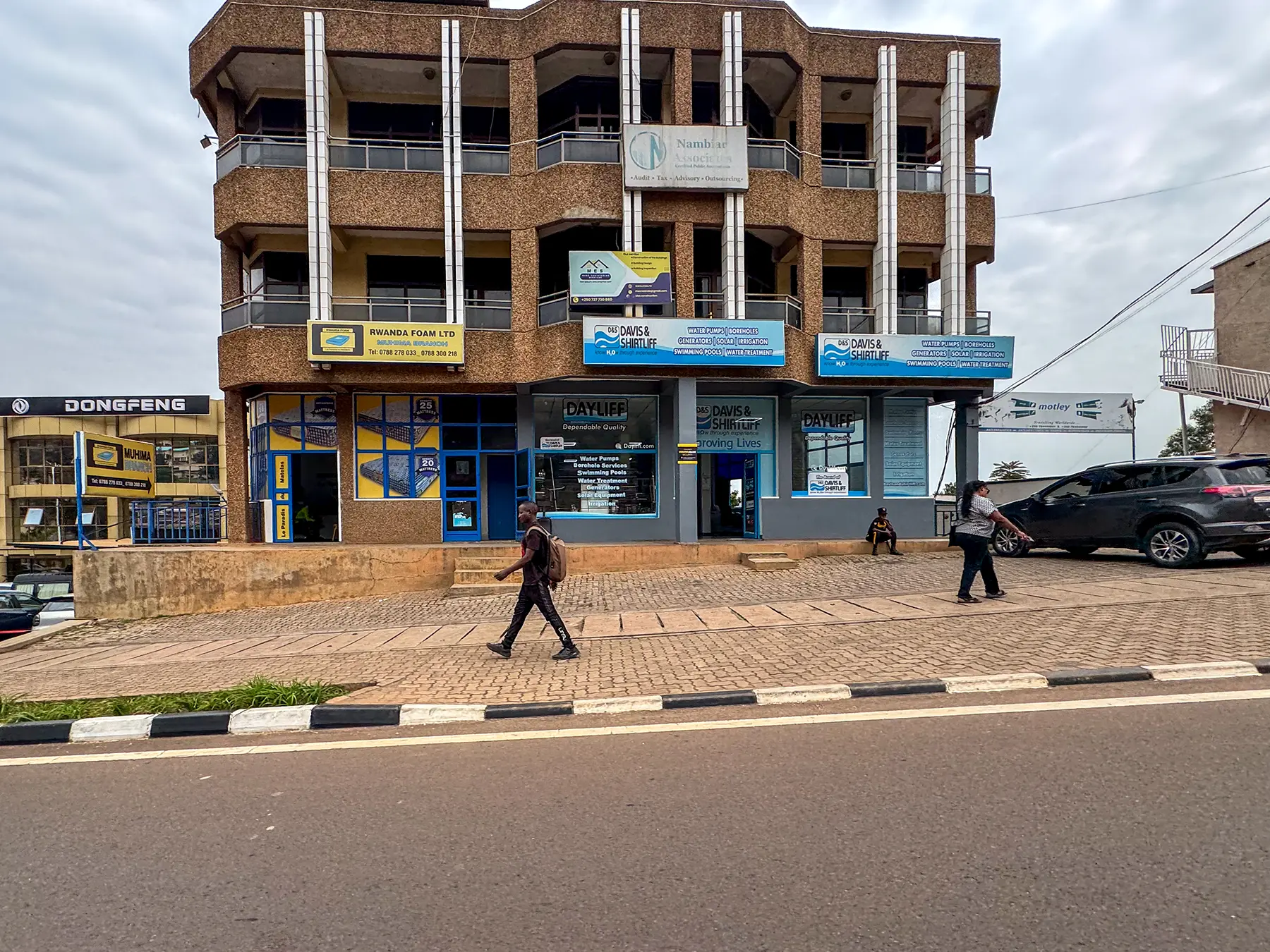 Three storey building with shopfronts and pedestrians along the pavement at commercial street in Kigali, Rwanda