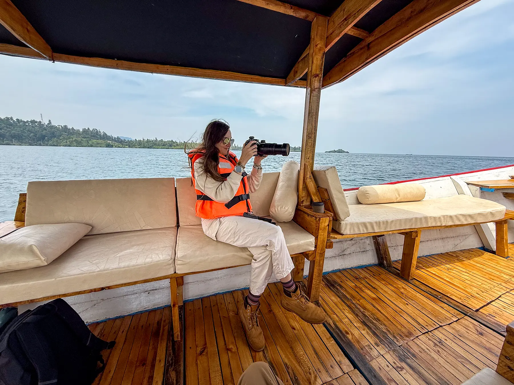 Ella McKendrick photographs the shoreline from a wooden boat at Lake Kivu, Rwanda