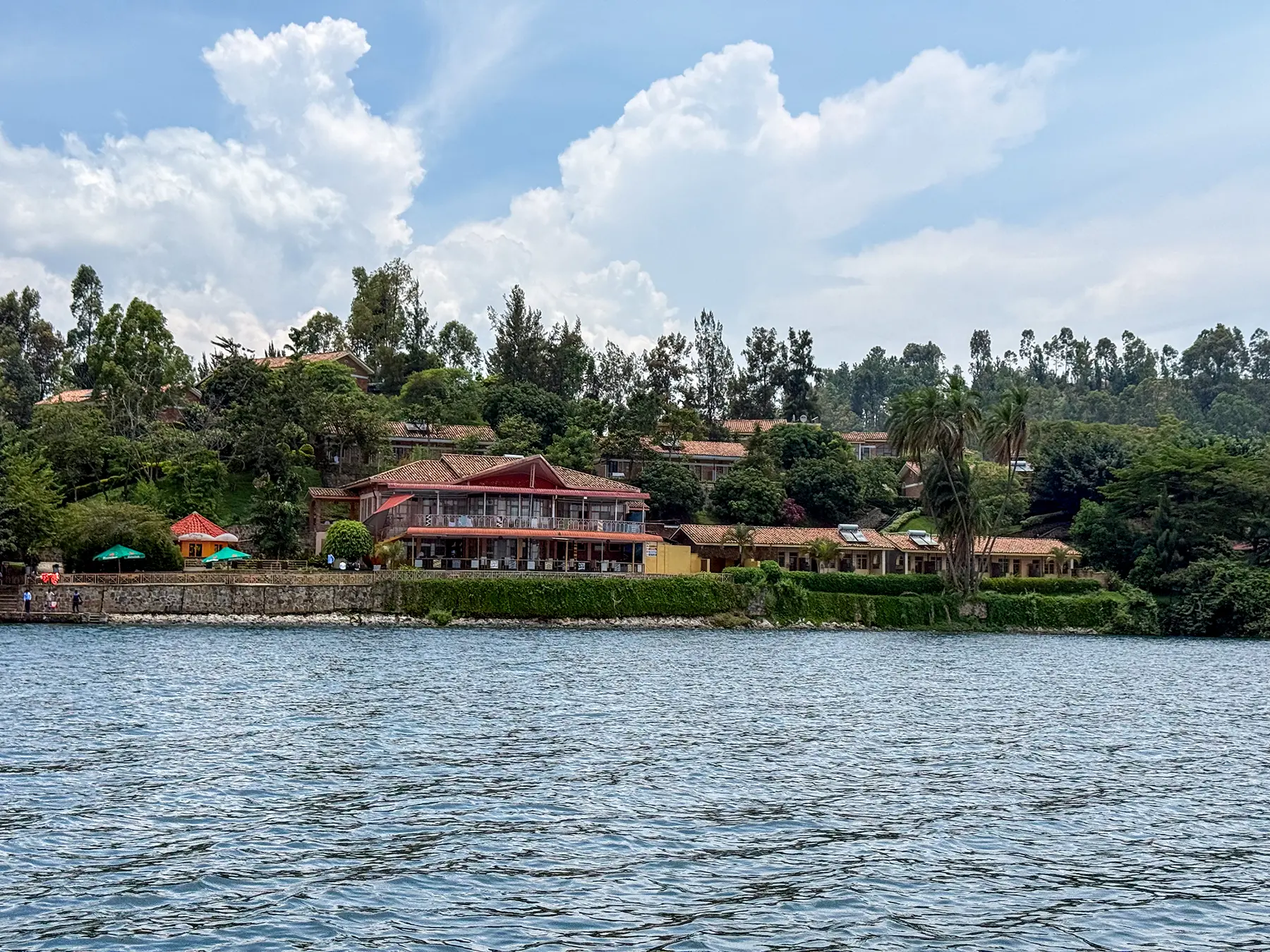 Lakeside lodge with red roof and waterfront gardens viewed from the water at Lake Kivu, Rwanda
