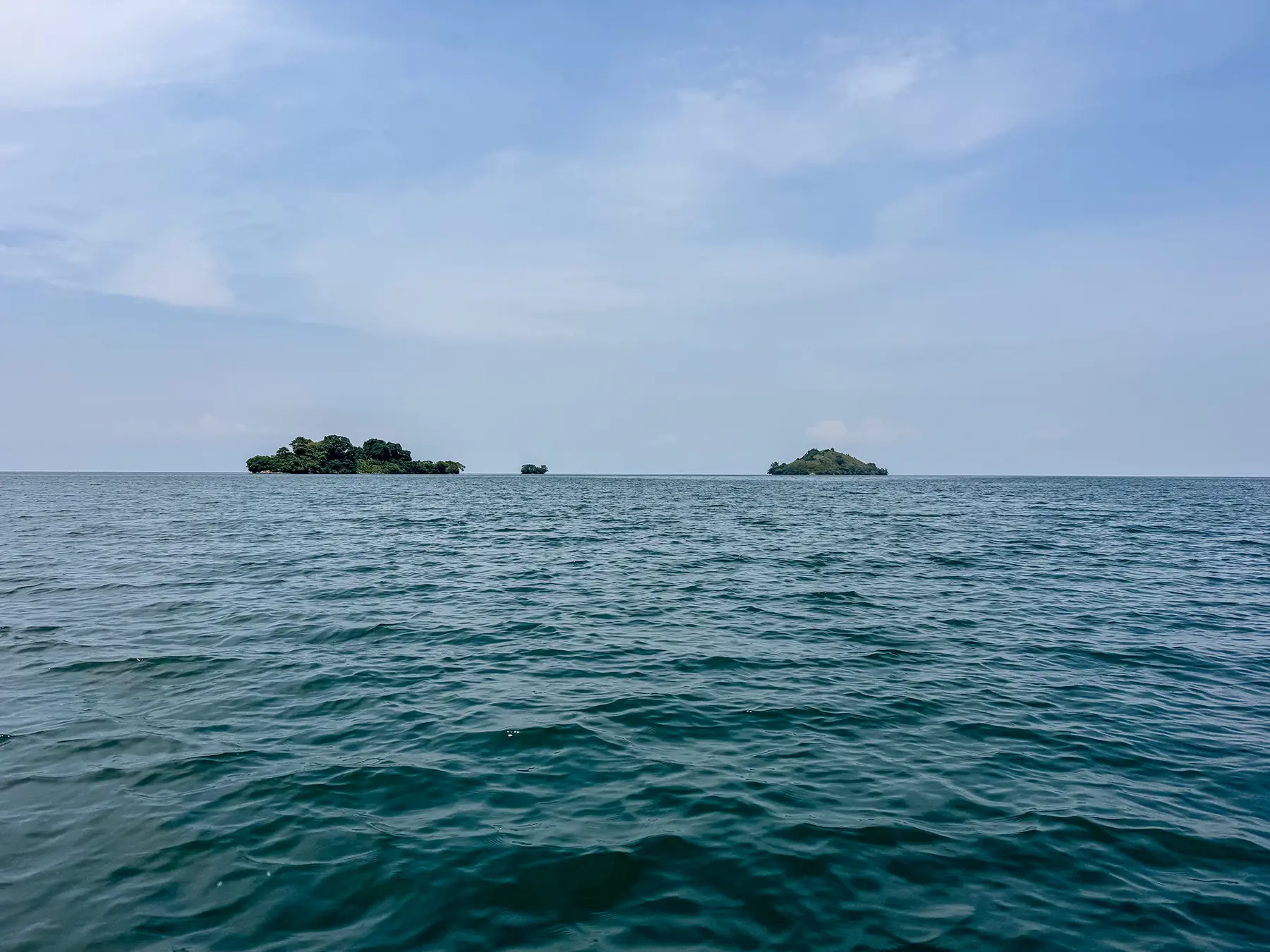 Three small forested islands rising from open water at Lake Kivu, Rwanda