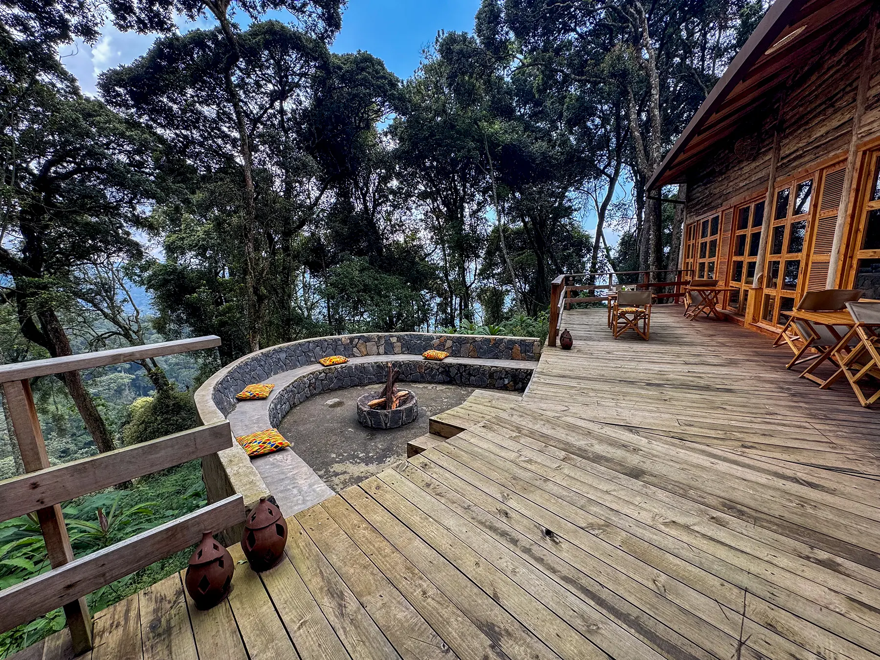 Wooden deck with curved fire pit seating and forest canopy views at Munazi Lodge in Nyungwe National Park, Rwanda