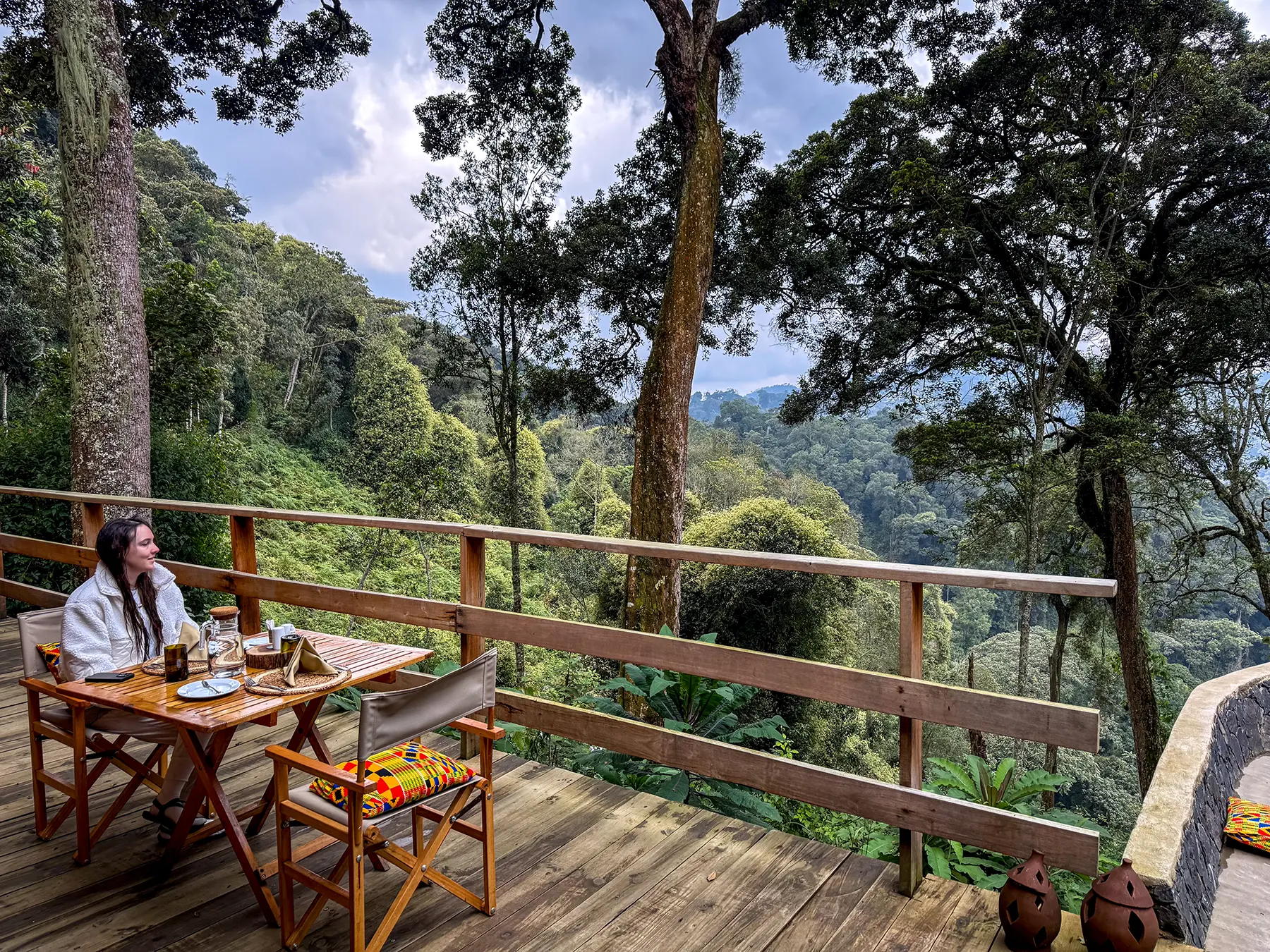 Ella McKendrick at breakfast table on lodge deck with rainforest view at Munazi Lodge in Nyungwe National Park, Rwanda